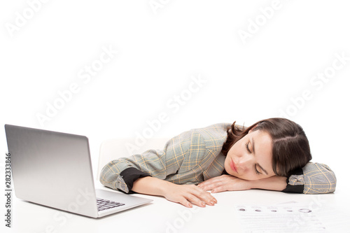 Young tired female student or office worker sleeping on desk in front of laptop
