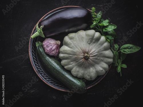 Eggplant, zucchini, garlic, patizon and basil on vintage metal plate. Overhead shot. photo