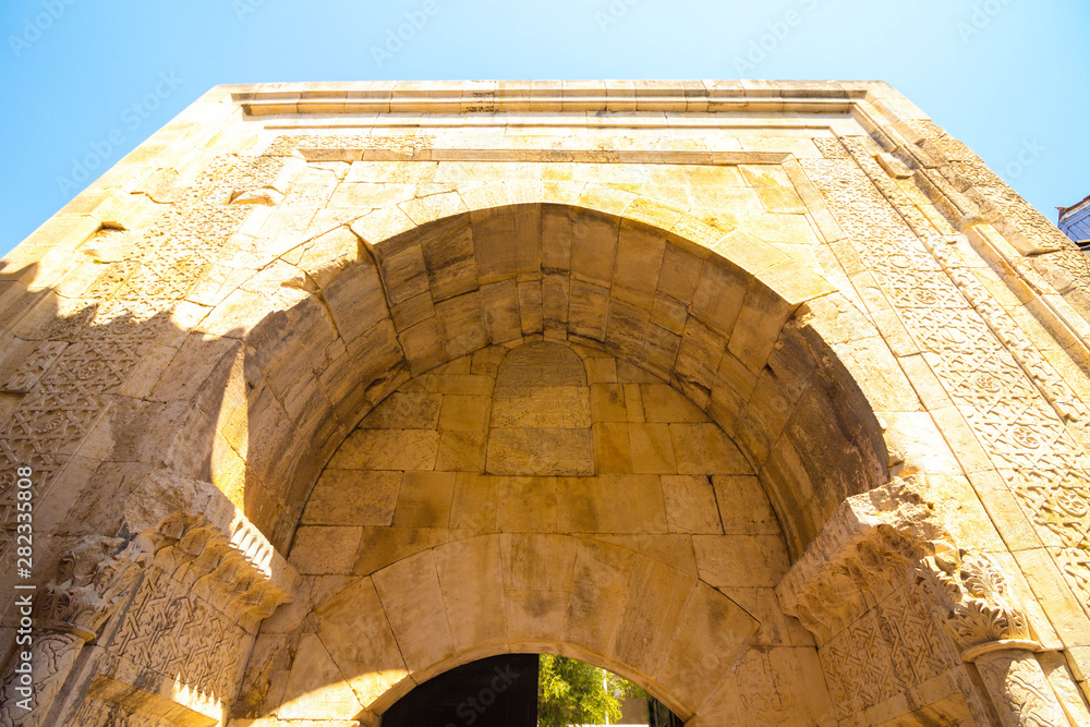 The high arch is built of stone blocks. The arch serves as a passage to the ancient part of the city. Arch on a background of clear and blue sky.