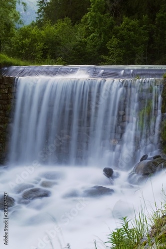 A waterfall immersed in the nature of the Italian Alps, near the town of Ponte di Legno - June 2019.