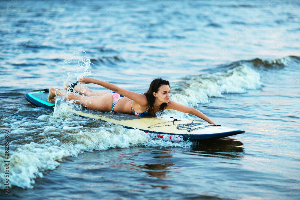 Beautiful fit surfing girl on surfboard on in the ocean. Woman ride good wave.