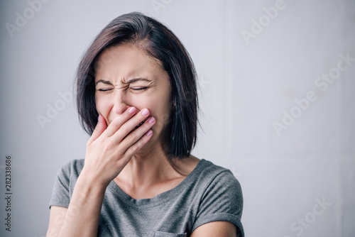 depressed brunette woman crying and covering mouth at home