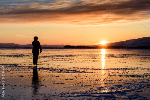 silhouette of a woman skating on the ice floor on the lake baikal with sunset.
