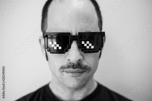 White man with funny glasses and a prominent mustache looks at the camera photo