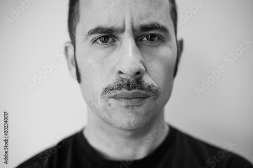 White man with a prominent mustache looking straight at the camera against a seamless background