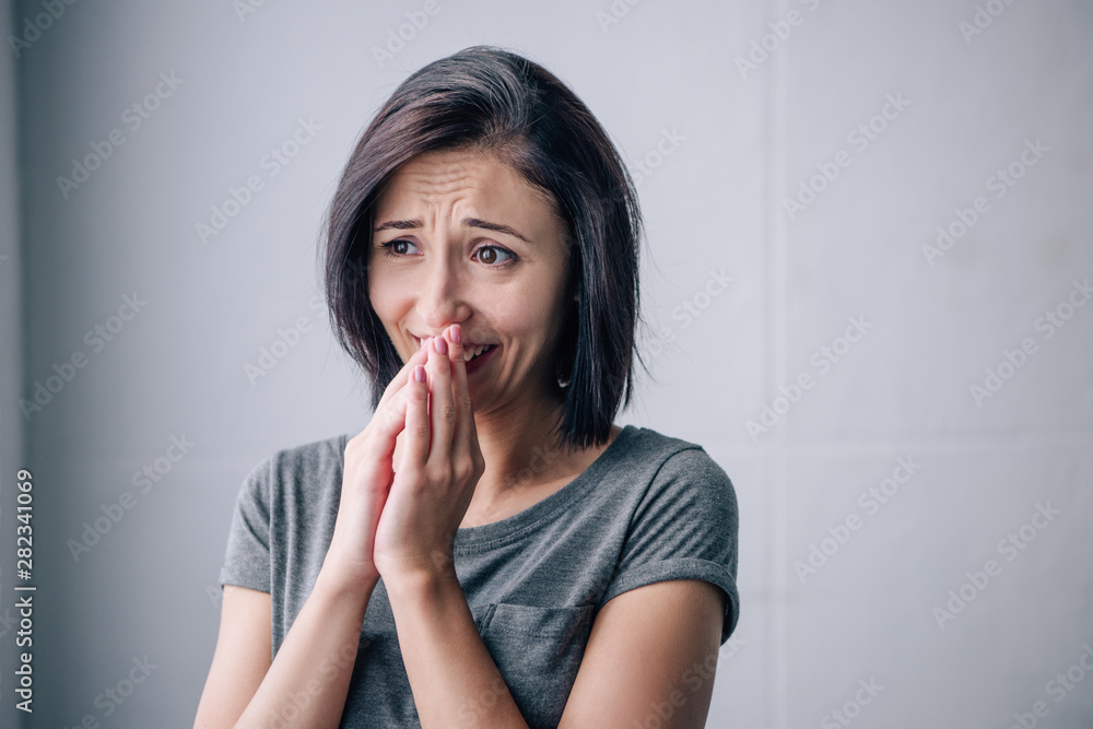 sad brunette woman covering mouth and crying at home sad brunette woman covering mouth and crying at home