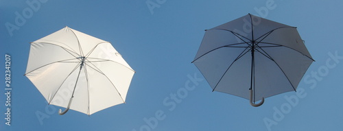 Dois guarda-chuvas brancos a flutua no c  u um claro e um escuro