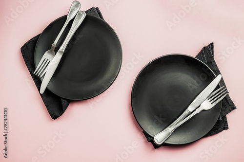 Black setting: plates, inen napkin and silverware on pink background. Top view. photo