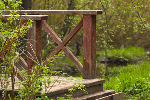 Wooden perial of the bridge through the forest river in the spring park