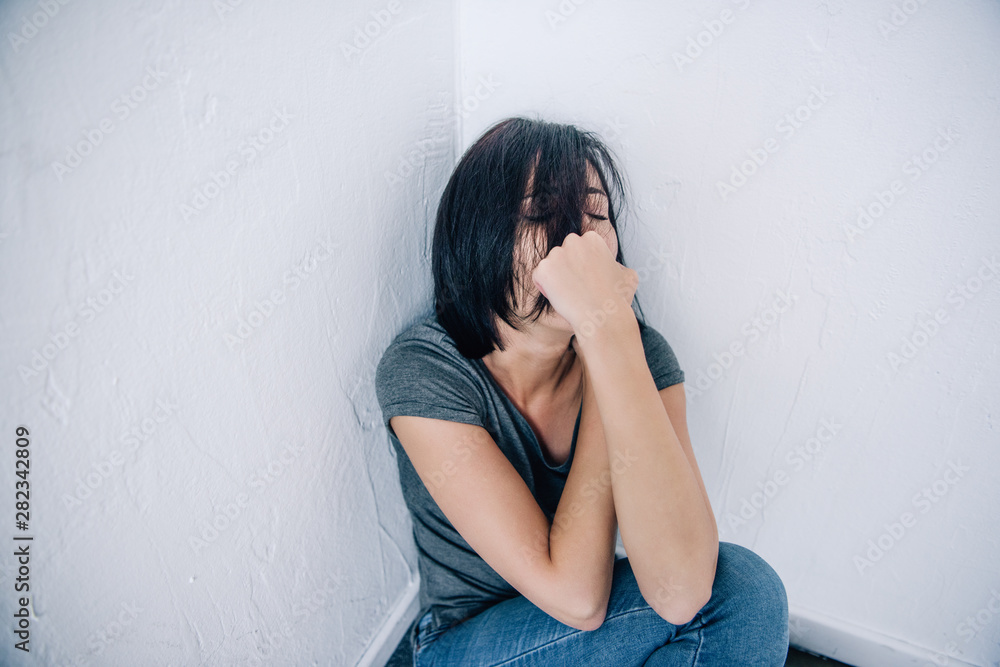 depressed brunette woman sitting and covering mouth at home depressed brunette woman sitting and covering mouth at home