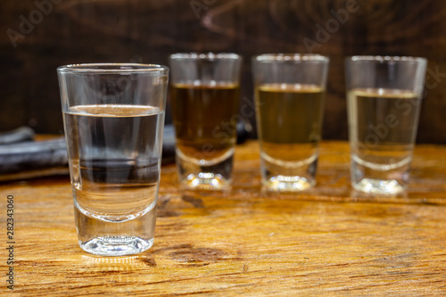 Several glasses of brazilian cachaça isolated on rustic wooden background, variations and types of brazil cachaça, typical drink from brazil.