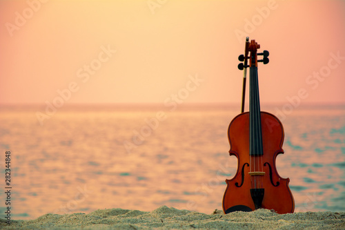 Close up of a Violin at the beach with sunset background