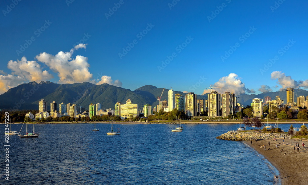 Beautiful skyline of Vancouver city at Vancouver Harbor , Harbor, yacht near the beach,  Downtown and Stanley Park on the background of a mountain range and blue cloudy sky 