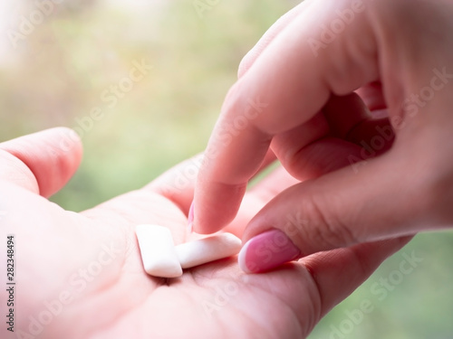 Female fingers take chewing gum from a palm.