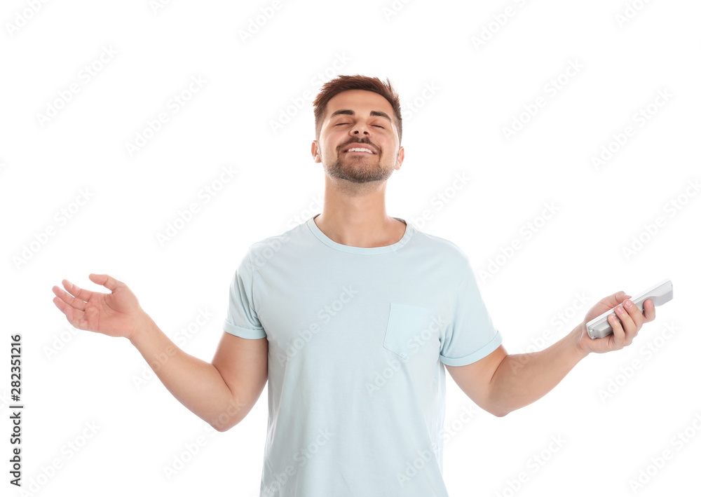 Happy young man with air conditioner remote control on white background