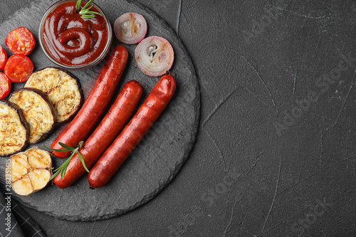 Flat lay composition with delicious grilled sausages on black table, space for text. Barbecue food