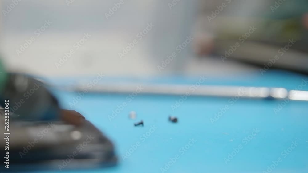 Smartphone assembling in repair shop. Lift up a screw with a magnet screwdriver and then screw it in. Mobile phone maintenance service Smartphone assembling in repair shop. Lift up a screw with a magnet screwdriver and then screw it in. Mobile phone maintenance service