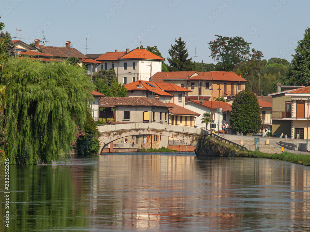 Fototapeta premium landscape on the outskirts of Milan, a colorful village is reflected in the navigable canal of the Naviglio Grande.Italy