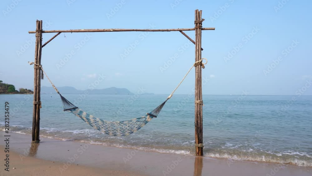 Empty net hammock at the beach above shallow ocean waters Empty net hammock at the beach above shallow ocean waters