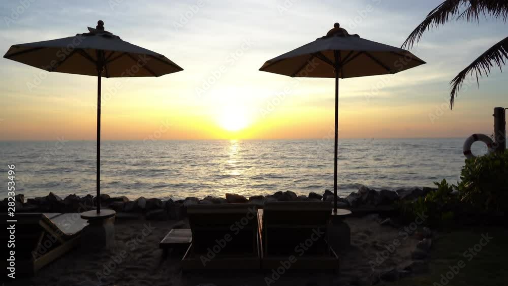 Umbrellas in silhouette in front of a tropical beach sunset. Static camera Umbrellas in silhouette in front of a tropical beach sunset. Static camera