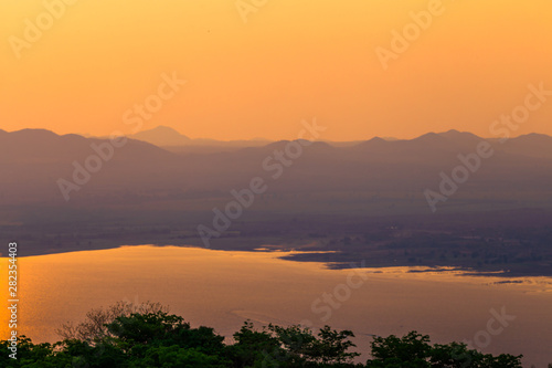 Natural panoramic wallpaper of high mountain scenery, overlooking the atmosphere of rivers, grasslands, roads, and the orange sunshine in the evening, blown through blurred cool air.
