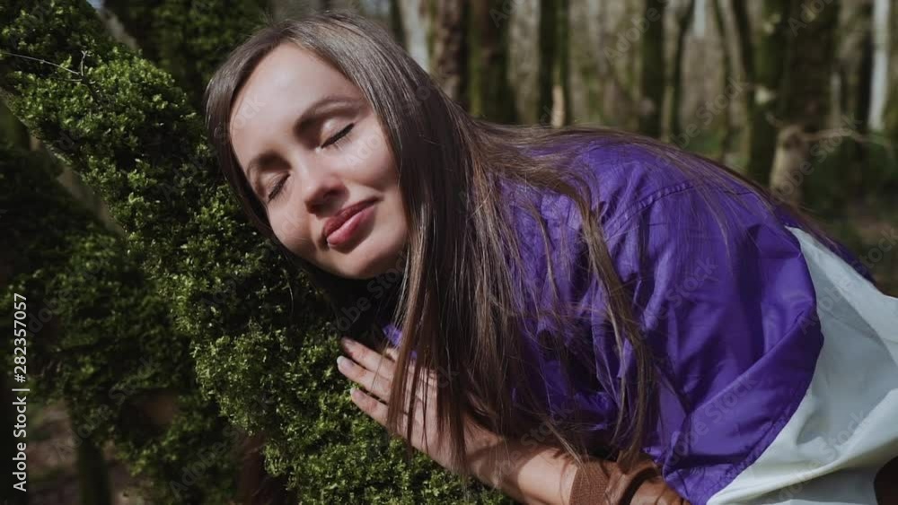 Girl puts her head on tree trunk which is covered with moss and falls asleep Girl puts her head on tree trunk which is covered with moss and falls asleep