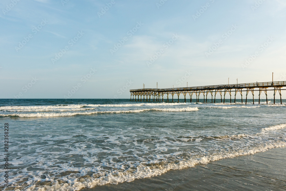 Pier into the Atlantic Ocean, Sunset Beach, North Carolina; with copy space for text, at sunrise