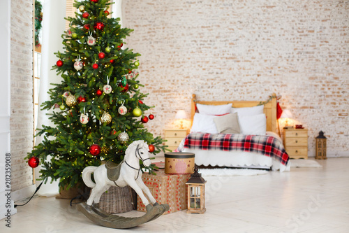 Classic Christmass or New Year decoration in a bedroom. Toy horse, spruce, classic decorations. Vintage New Year decore. Christmas mood in children room