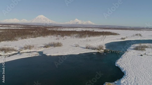 Flight over the winter river with a view of the volcanoes of Kamchatka