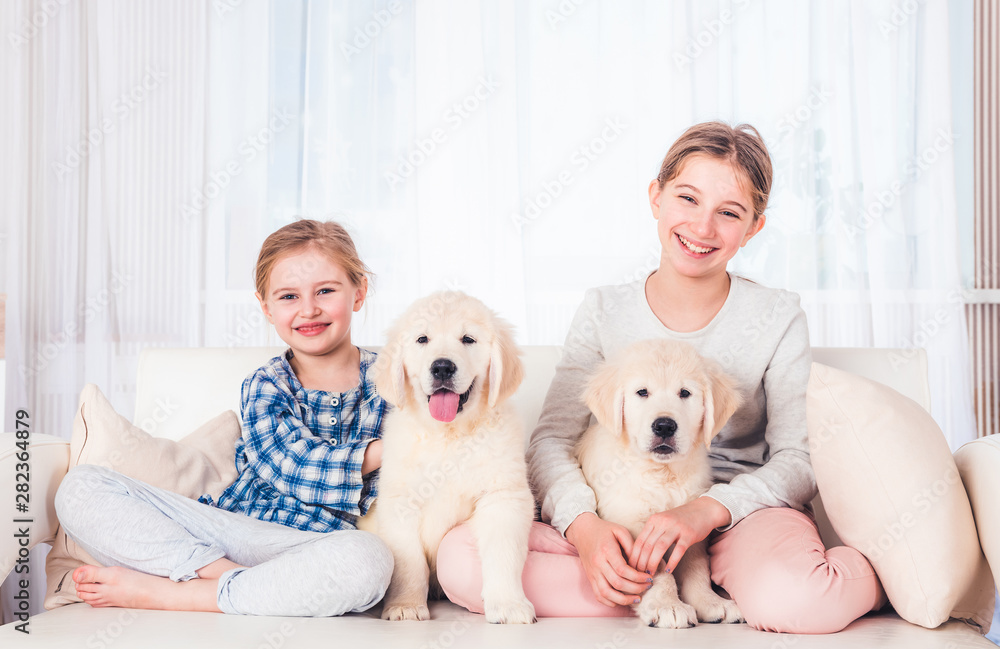 Smiling sisters sitting with puppies Smiling sisters sitting with puppies