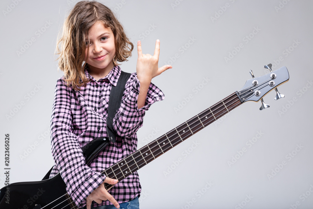 Fototapeta premium Smiling girl playing guitar giving a horns sign