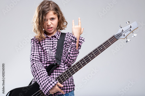 Girl playing guitar giving a Devil Horns sign