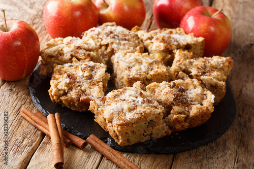 Sliced apple blondies with cinnamon and nuts close-up on a slate board on the table. horizontal