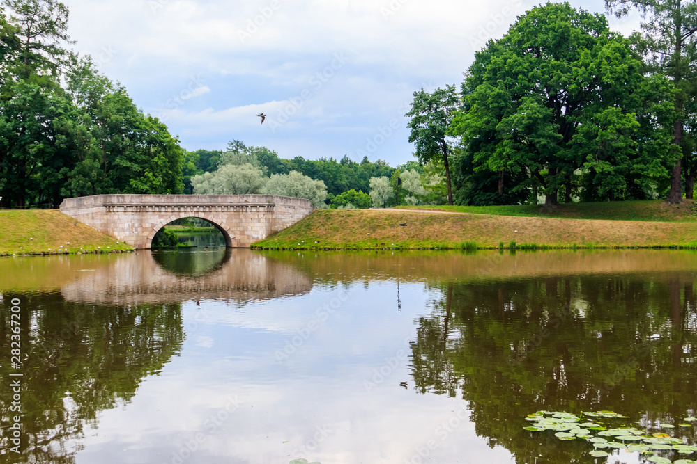 Fototapeta premium Stone arch bridge across a lake in Gatchina, Russia