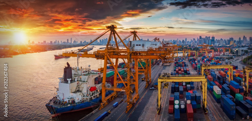 Logistics and transportation of Container Cargo ship and Cargo plane with working crane bridge in shipyard at sunset, logistic import export and transport industry background