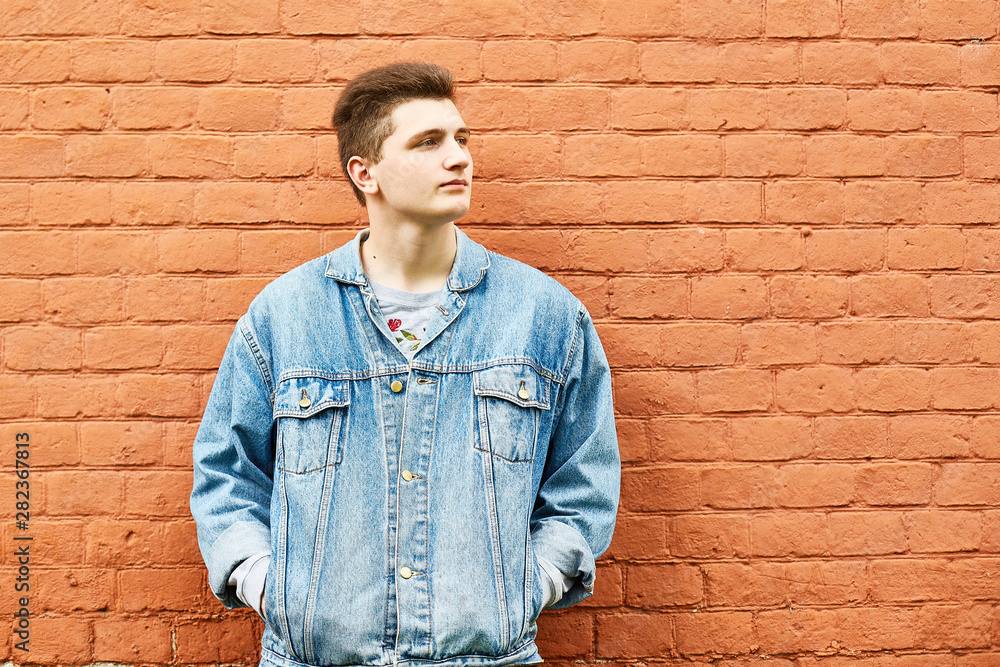 young guy in a denim jacket against a brick wall. copyspace young guy in a denim jacket against a brick wall. copyspace
