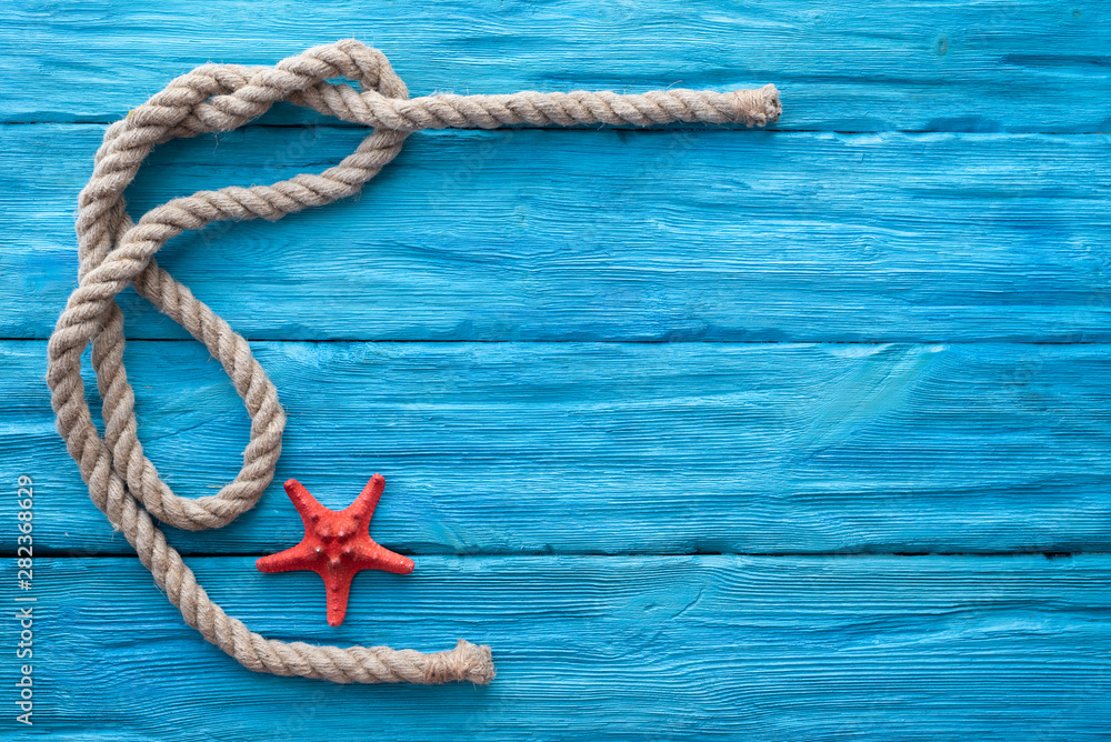 Mooring rope and red starfish on blue wooden table background with a ...