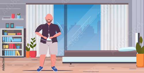 fat obese sad man buttoning shirt overweight casual guy standing pose unhealthy lifestyle obesity concept modern home apartment bedroom interior flat full length horizontal