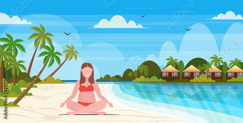 fat overweight woman in swimsuit plus size girl on beach sitting lotus pose summer vacation obesity concept tropical island seascape background full length flat horizontal