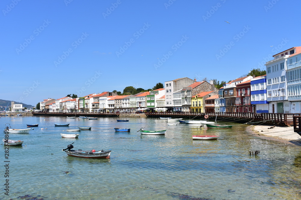 Small fishing village with boats and colorful houses. Blue sky, sunny day, Mugardos, Spain.