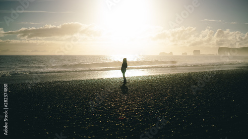 Silhouette of a lady looking at the sea during sunset time in a black sand beach in Iceland