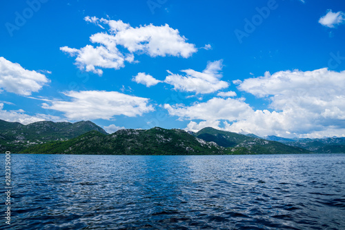 Montenegro, Green mountains alongside coast of lakeside of skadar lake waters viewed from boat in national park