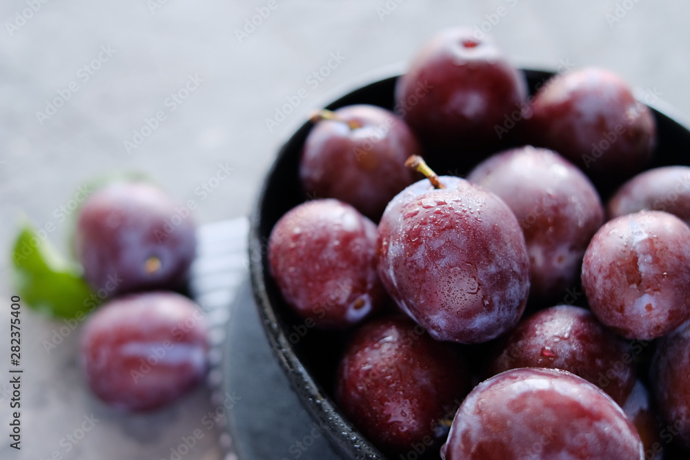 Fototapeta premium Fresh violet plums at dark wooden table background