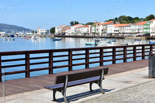 Small fishing village with boardwalk and wooden bench. Blue sky, sunny day, Mugardos, Spain. photo