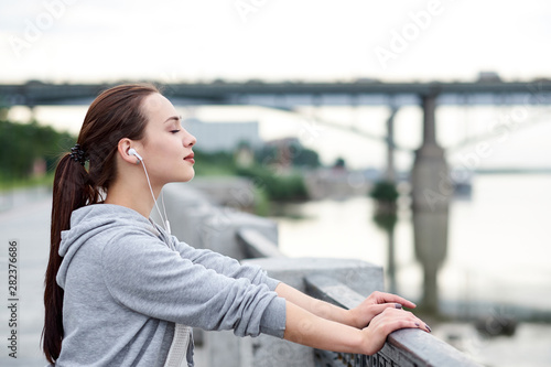 Fitness healthy asian woman runner relaxing after running outdoors enjoying view on waterfront