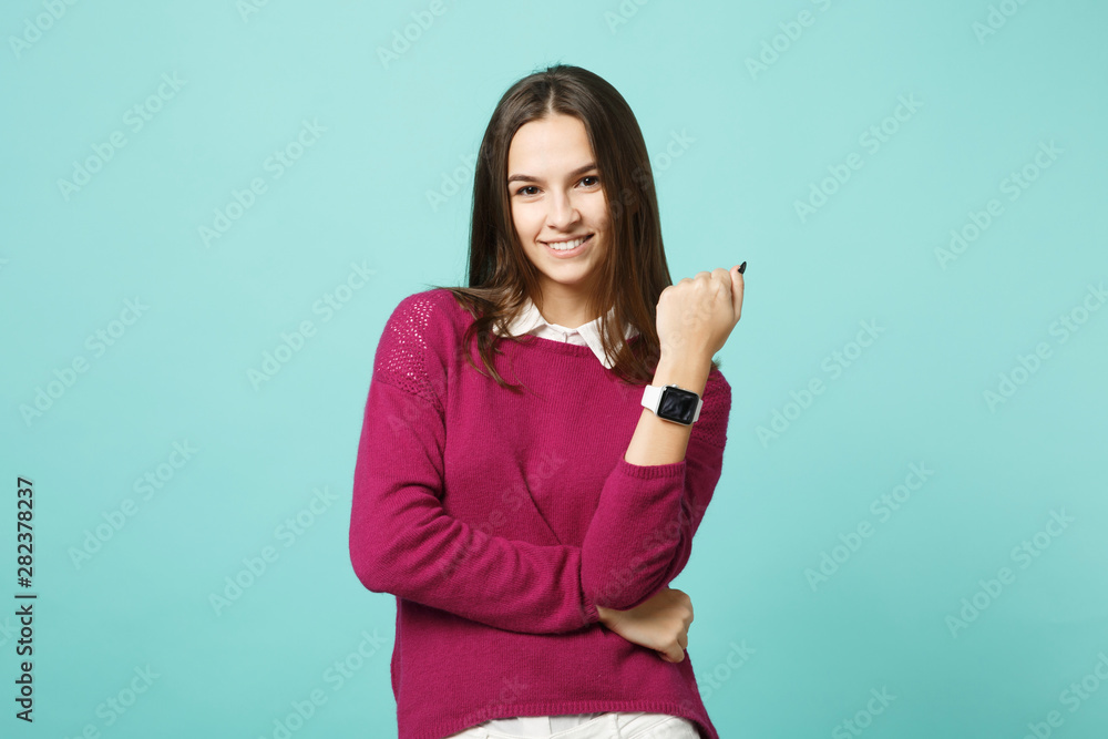 Young brunette woman girl in casual clothes posing isolated on blue green turquoise wall background studio portrait. People sincere emotions lifestyle concept. Mock up copy space. smart watch on hand. Young brunette woman girl in casual clothes posing isolated on blue green turquoise wall background studio portrait. People sincere emotions lifestyle concept. Mock up copy space. smart watch on hand.