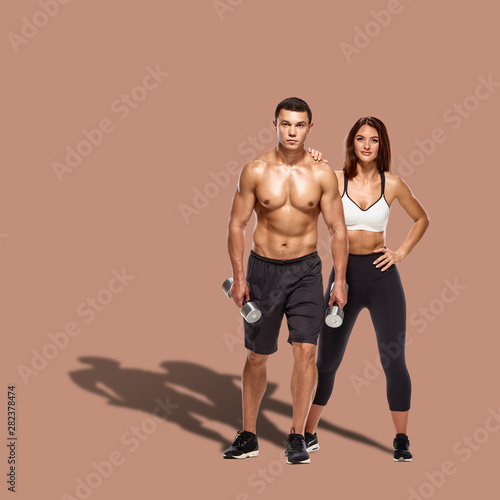 Healthy couple with dumbbells on brown background with shadow on floor © Denys Kurbatov