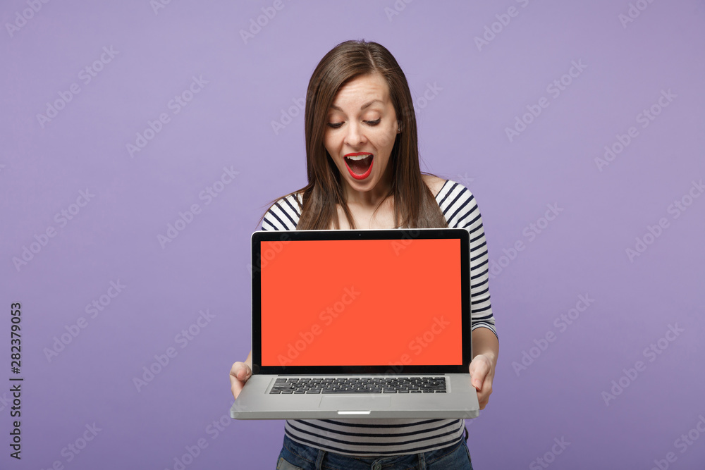Naklejka premium Young brunette woman girl in casual striped clothes posing isolated on violet purple background studio portrait. People sincere emotions lifestyle concept. Mock up copy space. Hold tablet pc computer.