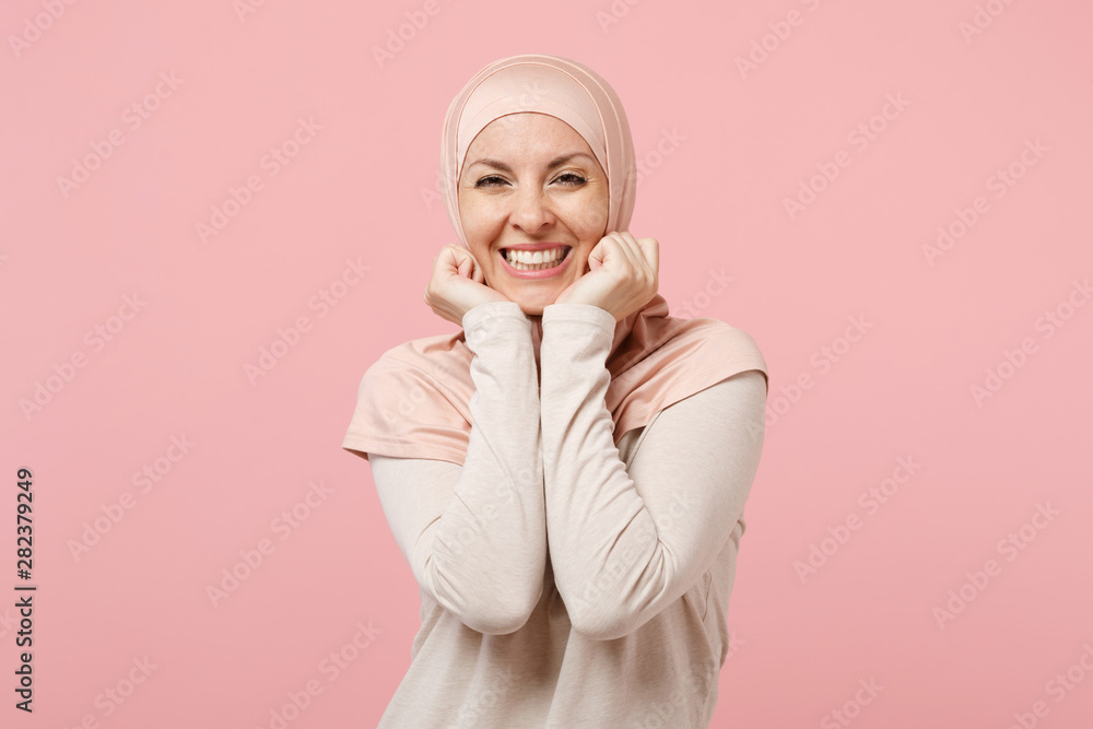 Joyful young arabian muslim woman in hijab light clothes posing isolated on pink background studio portrait. People religious Islam lifestyle concept. Mock up copy space. Keeping hands near cheeks. Joyful young arabian muslim woman in hijab light clothes posing isolated on pink background studio portrait. People religious Islam lifestyle concept. Mock up copy space. Keeping hands near cheeks.