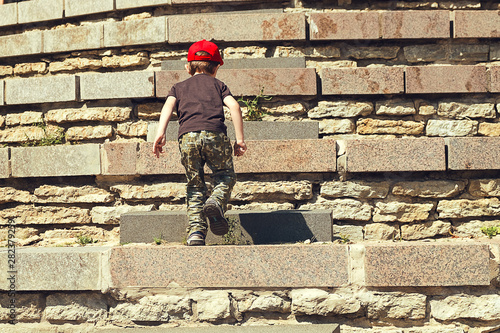 Little boy in red hat scaling the steps